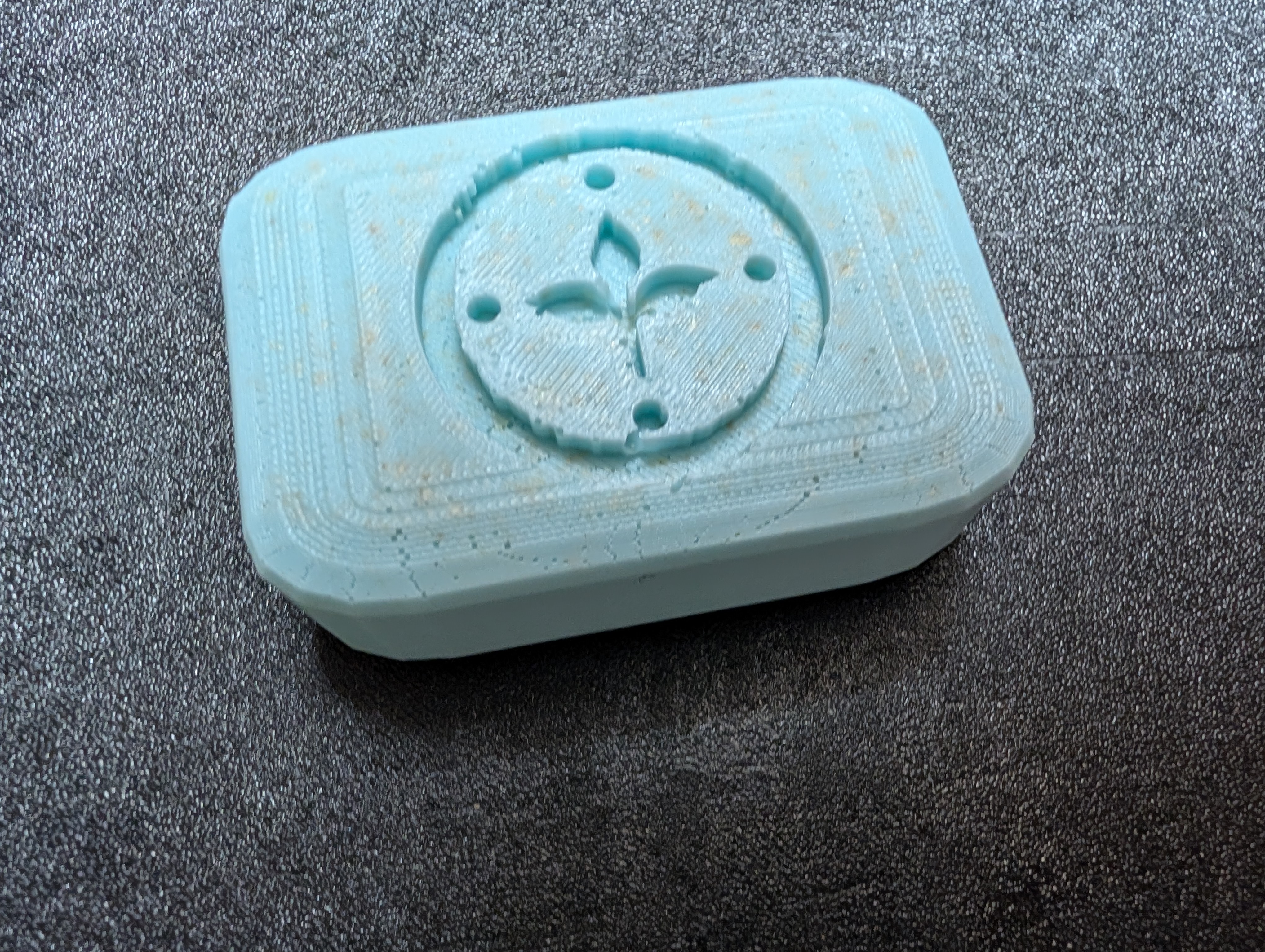 A handcrafted, light blue rectangular soap bar with the Stone Circle Herbals logo pressed into it.